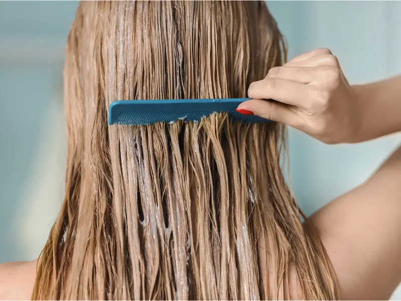 Woman combing hair with conditioner