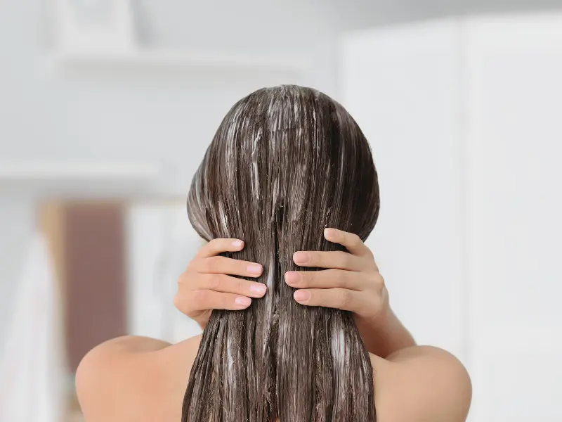 Woman in the shower applying hair conditioner